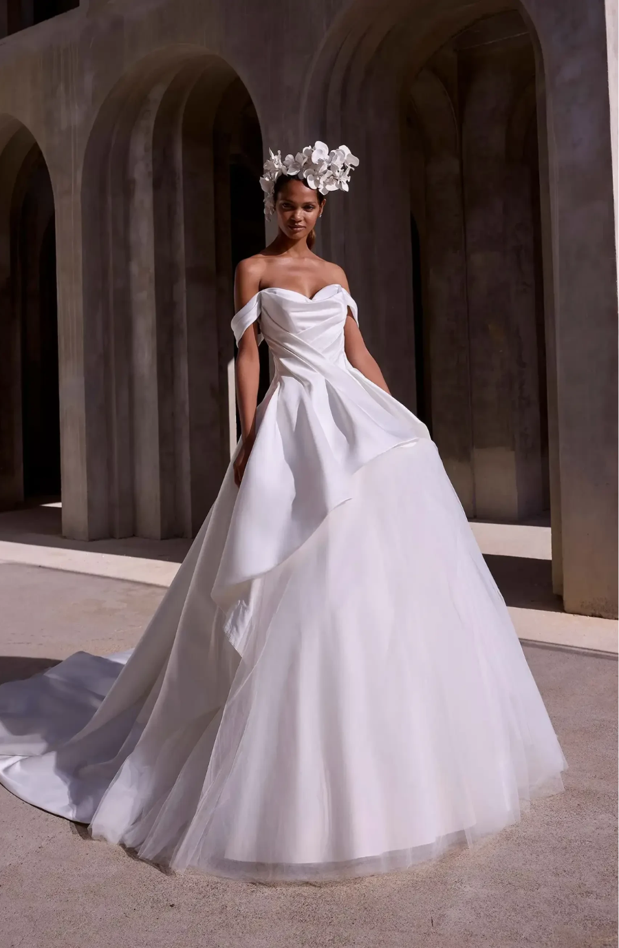 model is wearing an off the shoulder wedding dress