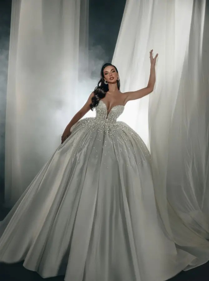 Model is wearing a strapless ball gown with a plunging neckline by sima couture