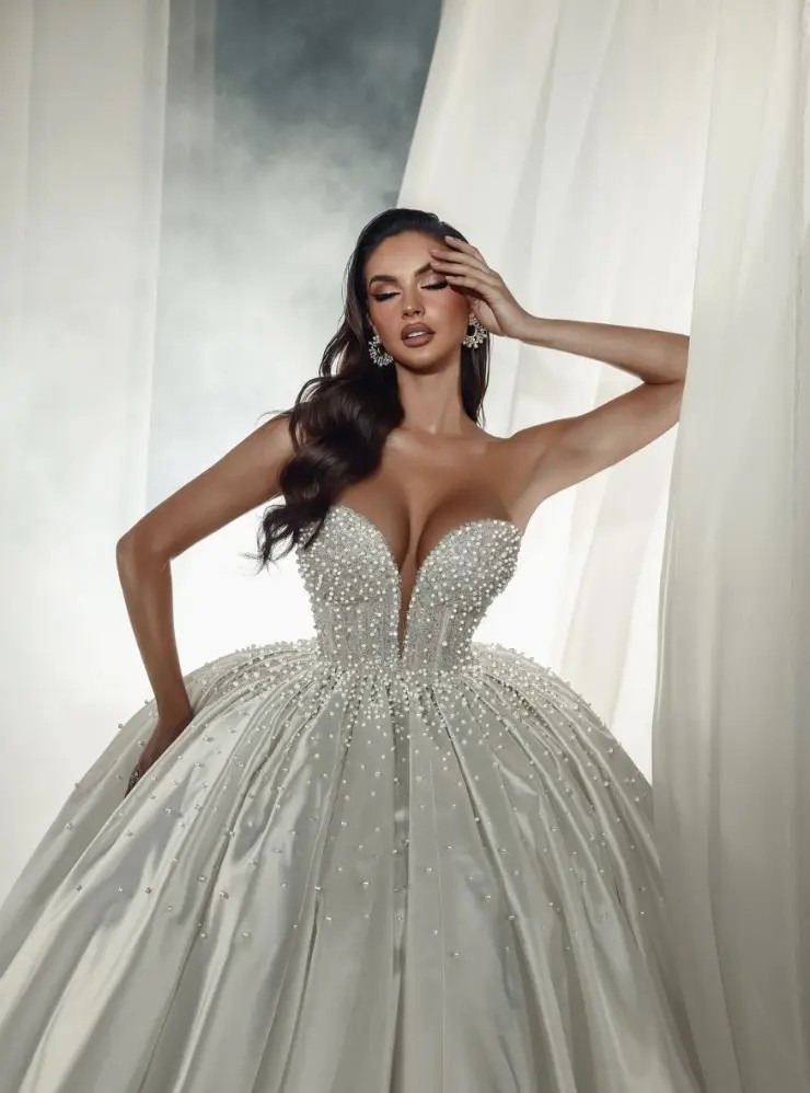 Model is wearing a strapless ball gown with a plunging neckline by sima couture