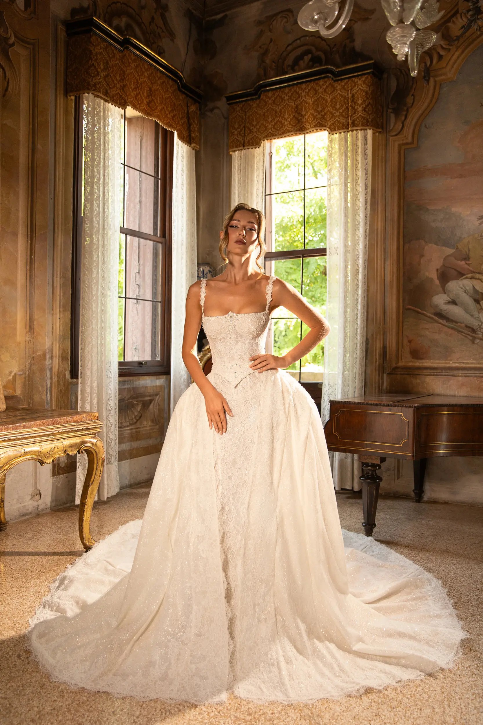 model is wearing a mermaid sleeveless wedding dress with an overskirt