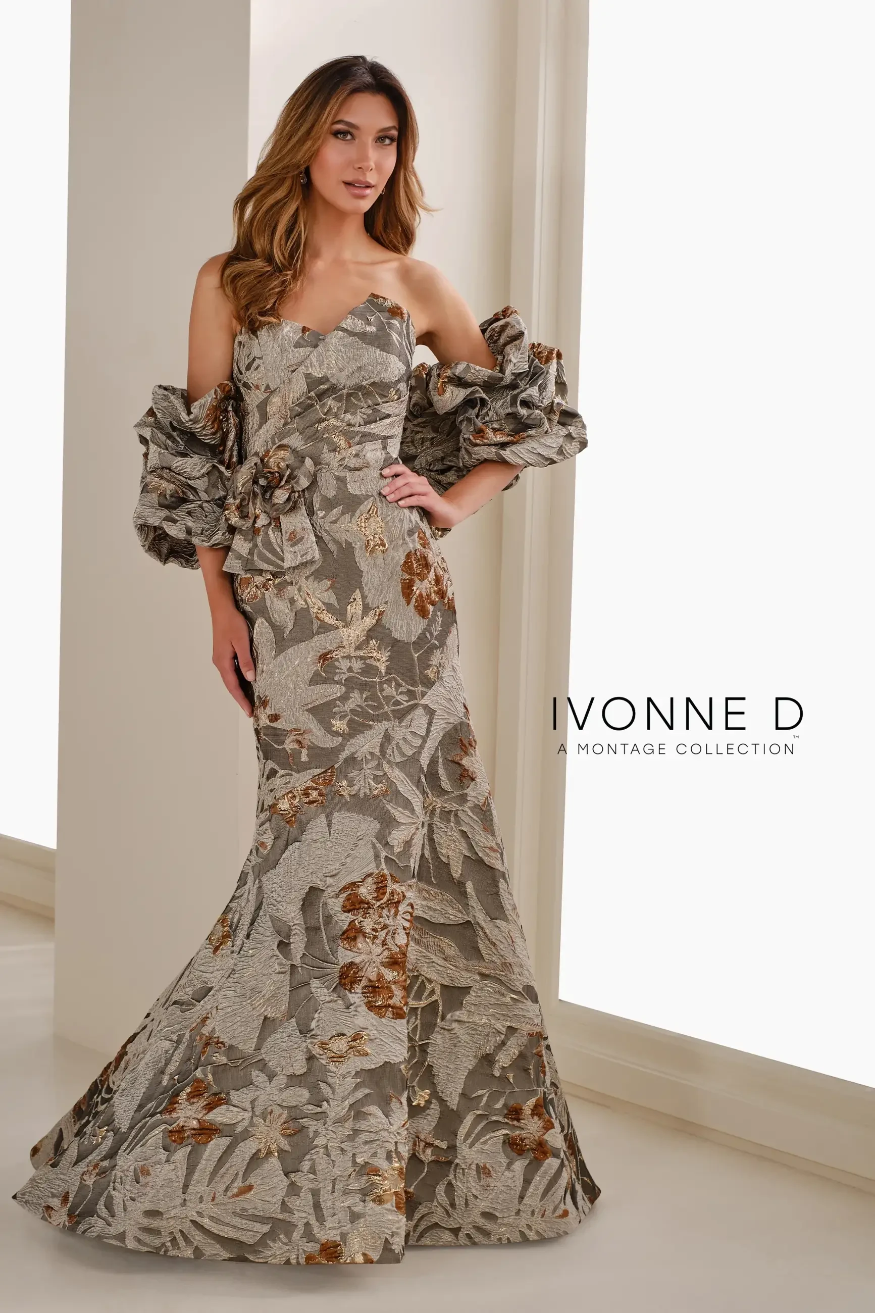A woman is wearing a floral evening gown with large puffed sleeves, posing in a well-lit indoor space. The dress has intricate patterns and a mermaid silhouette. The image includes the text 